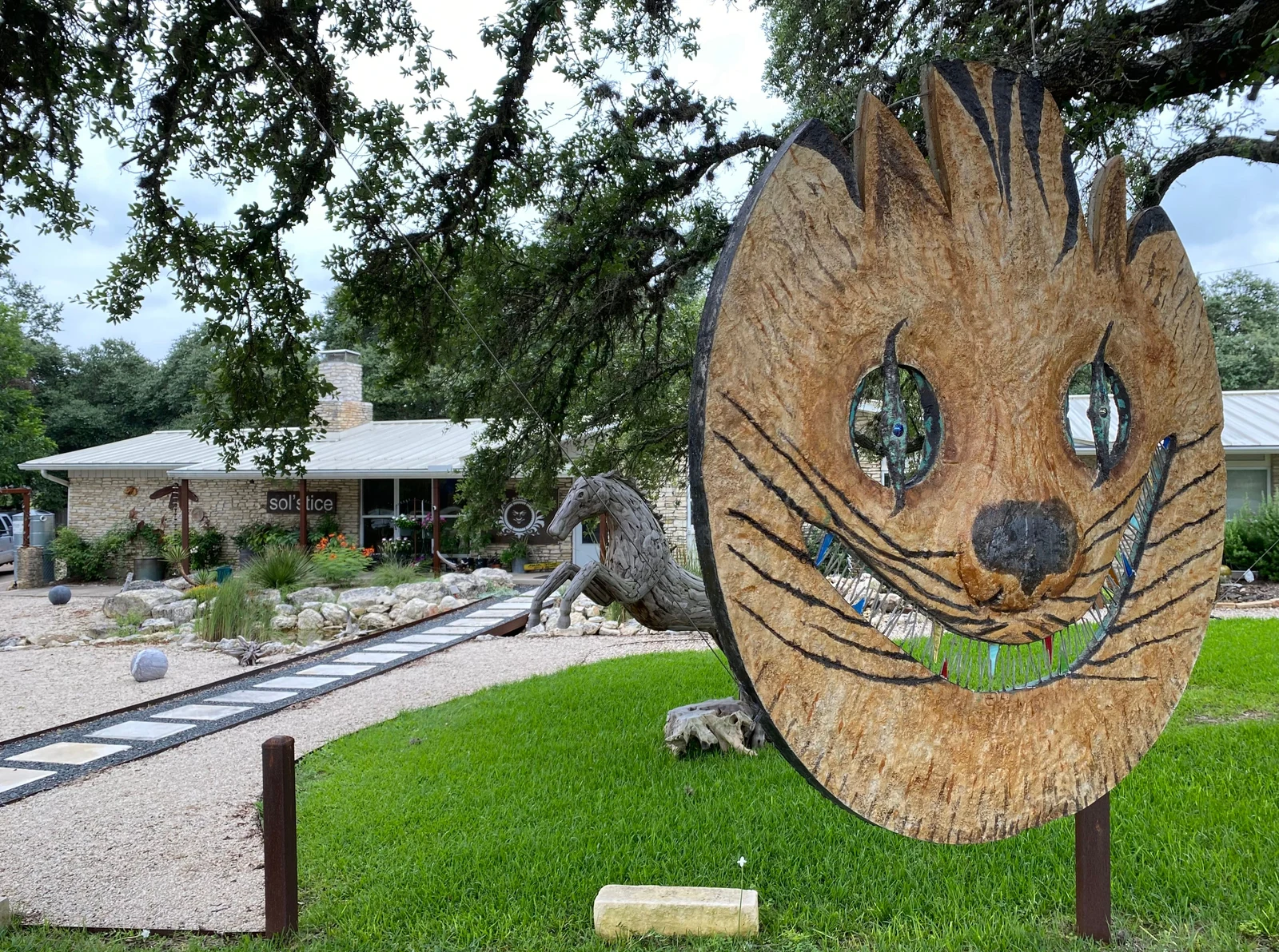 Cheshire Cat sculpture with the original Solstice storefront in the background