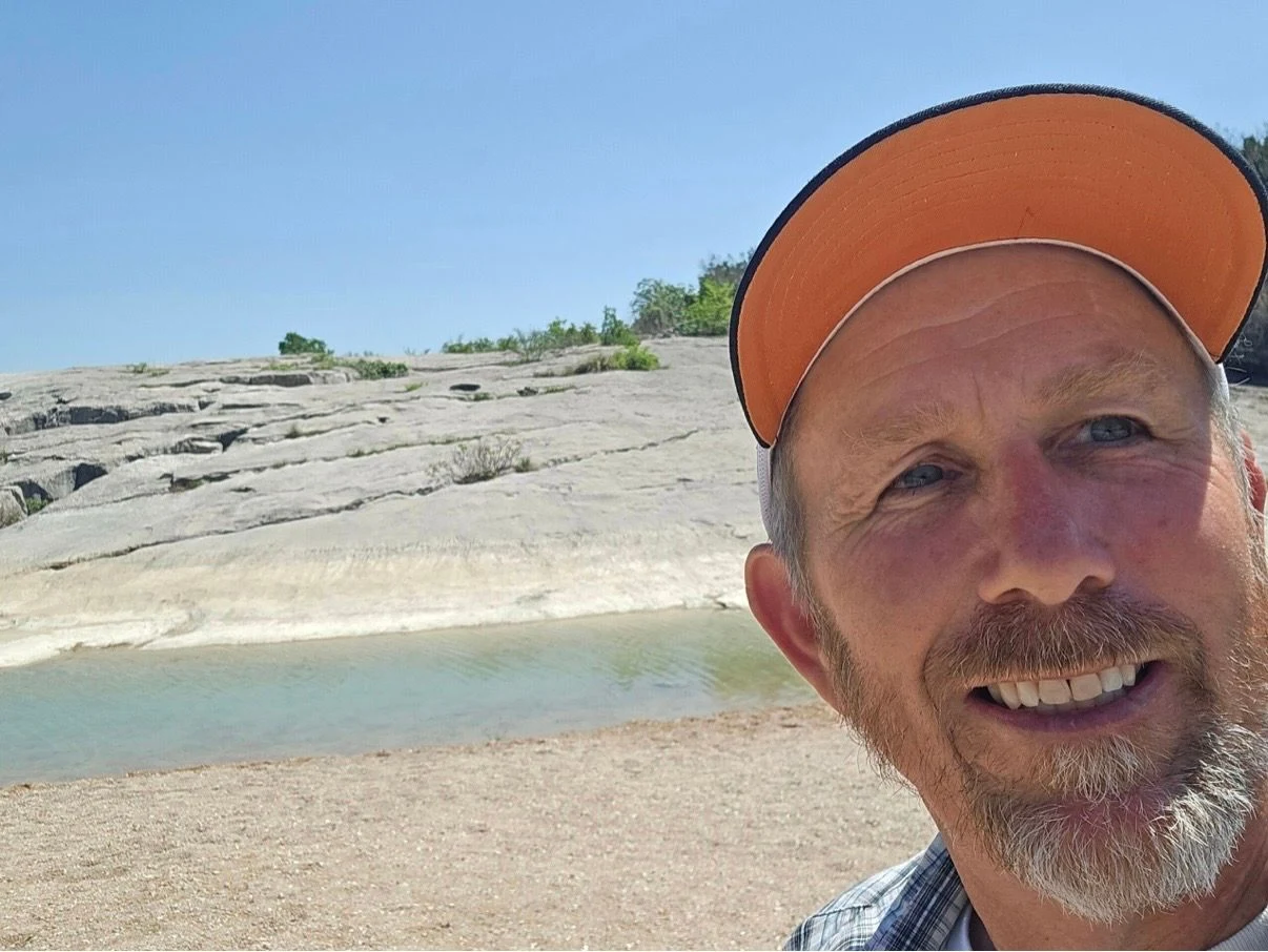 Christopher Sol Smartt outdoors beside a rocky creek